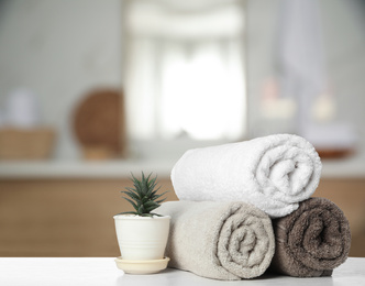 Image of Fresh towels and houseplant on white table in bathroom. Space for text