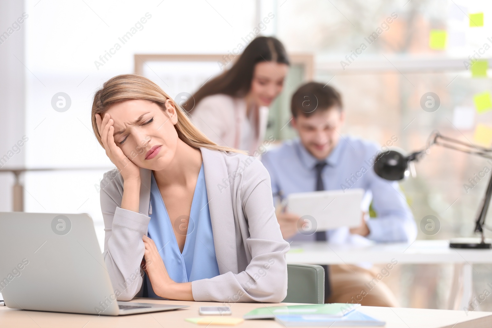 Photo of Young woman suffering from headache in office