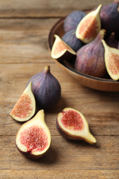 Whole and cut tasty fresh figs on wooden table