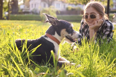 Teenage girl with her cute dog resting on green grass in park