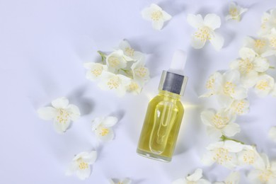 Photo of Essential oil in bottle and beautiful jasmine flowers on white background, flat lay