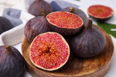 Photo of Fresh ripe purple figs on wooden plate, closeup