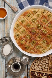 Delicious sweet baklava served on light blue wooden table, flat lay