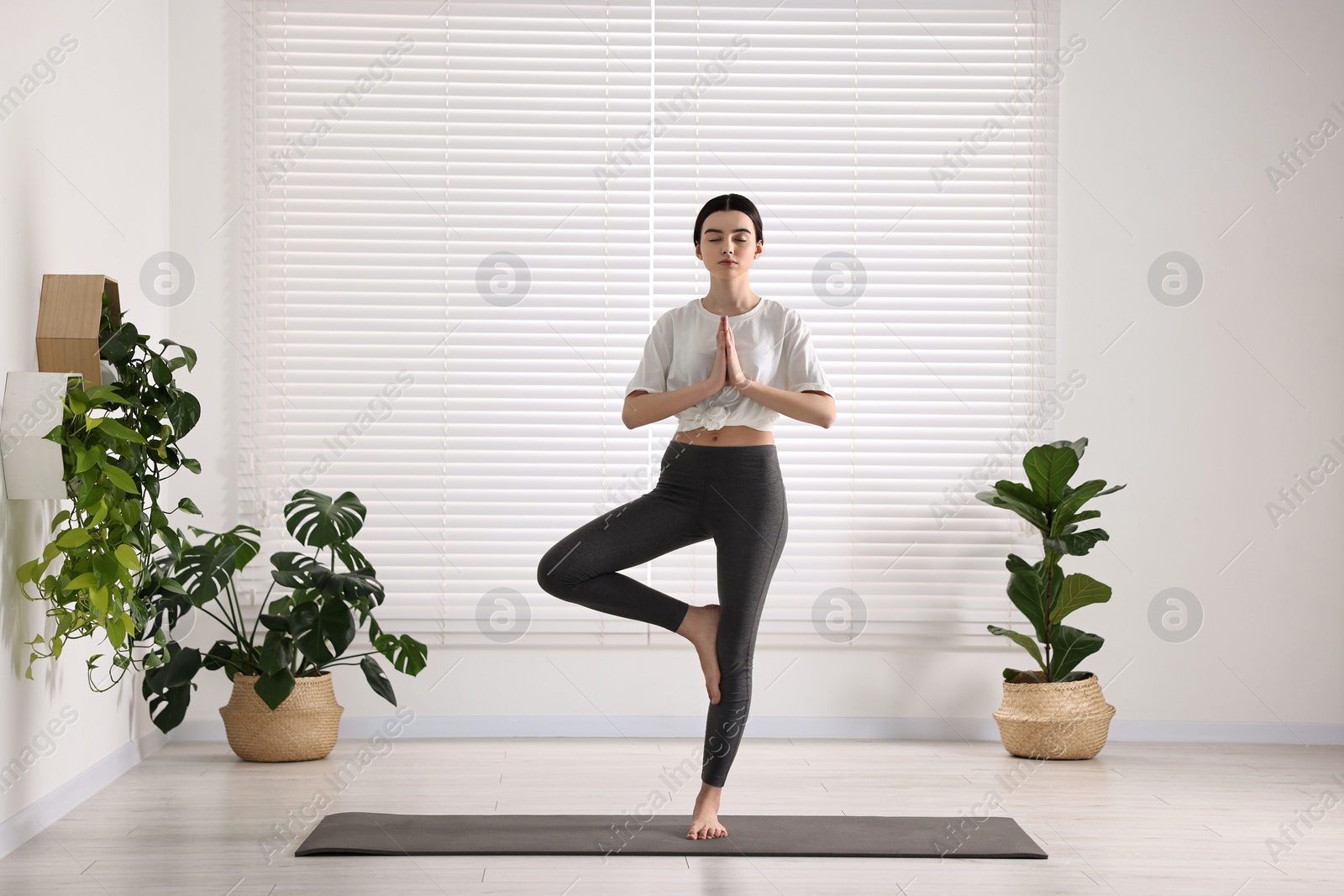 Photo of Girl practicing tree asana on mat in yoga studio. Vrksasana pose