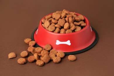 Dry dog food and feeding bowl on brown background