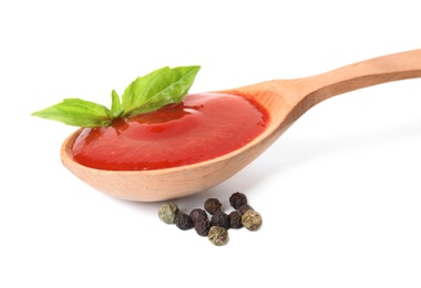 Photo of Spoon of tomato sauce with basil and pepper isolated on white