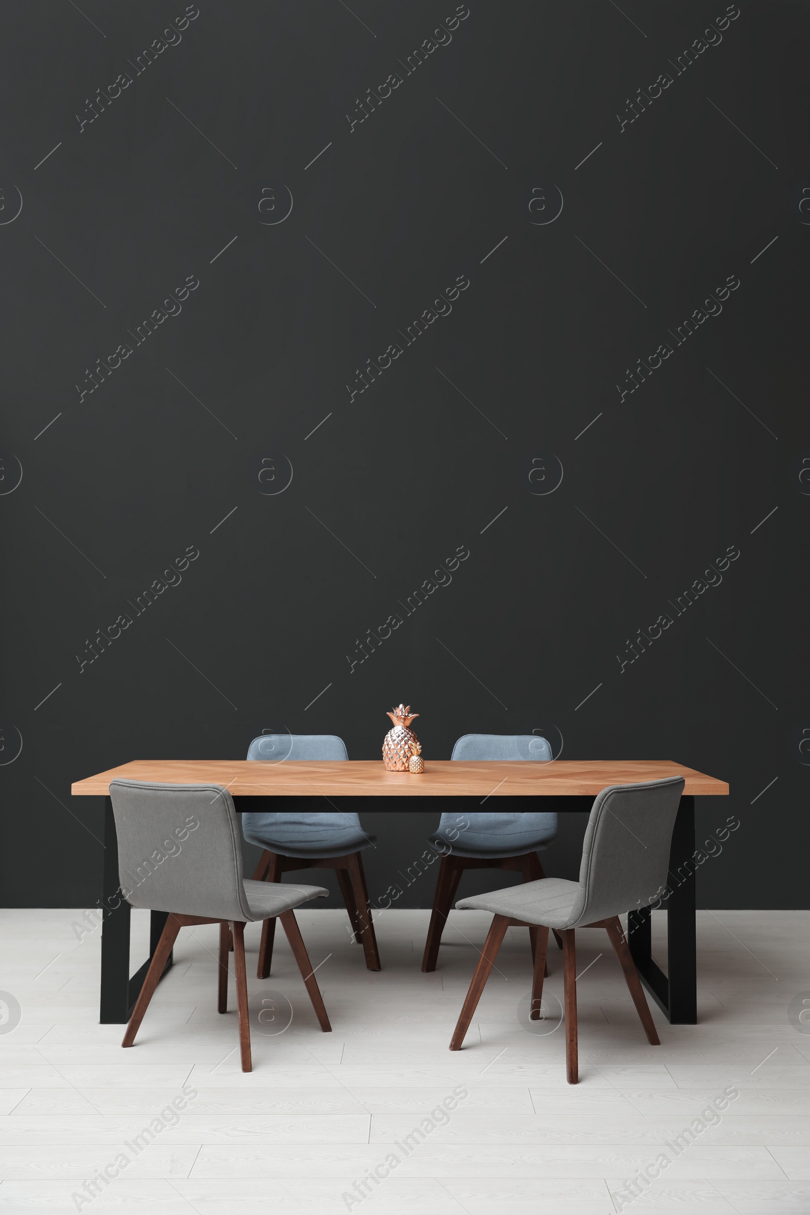 Photo of Modern table with decorative pineapples near black wall