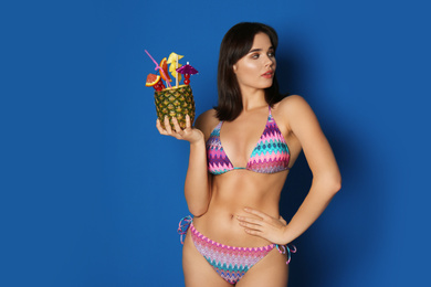 Photo of Beautiful young woman with exotic cocktail wearing bikini on blue background