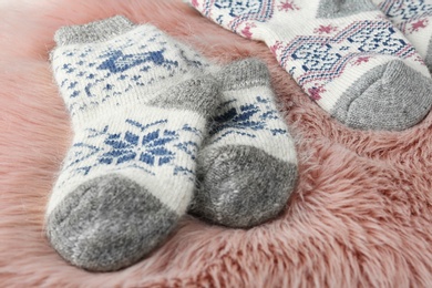 Photo of Knitted socks on pink faux fur, closeup