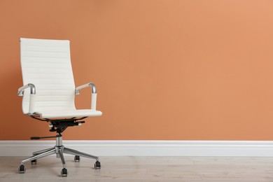 Photo of Modern office chair near orange coral wall indoors. Space for text