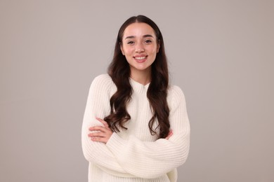 Beautiful young woman in stylish warm sweater on grey background