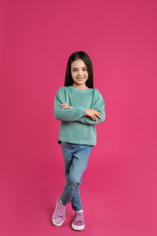 Photo of Cute little girl posing on pink background