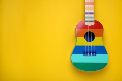 Colorful ukulele on yellow background, top view with space for text. String musical instrument