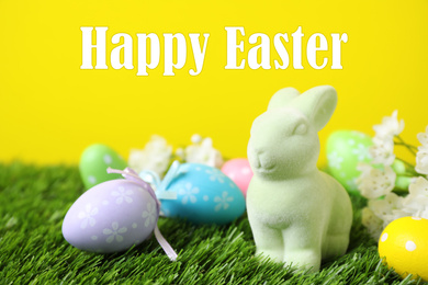 Image of Easter bunny toy and dyed eggs on green grass