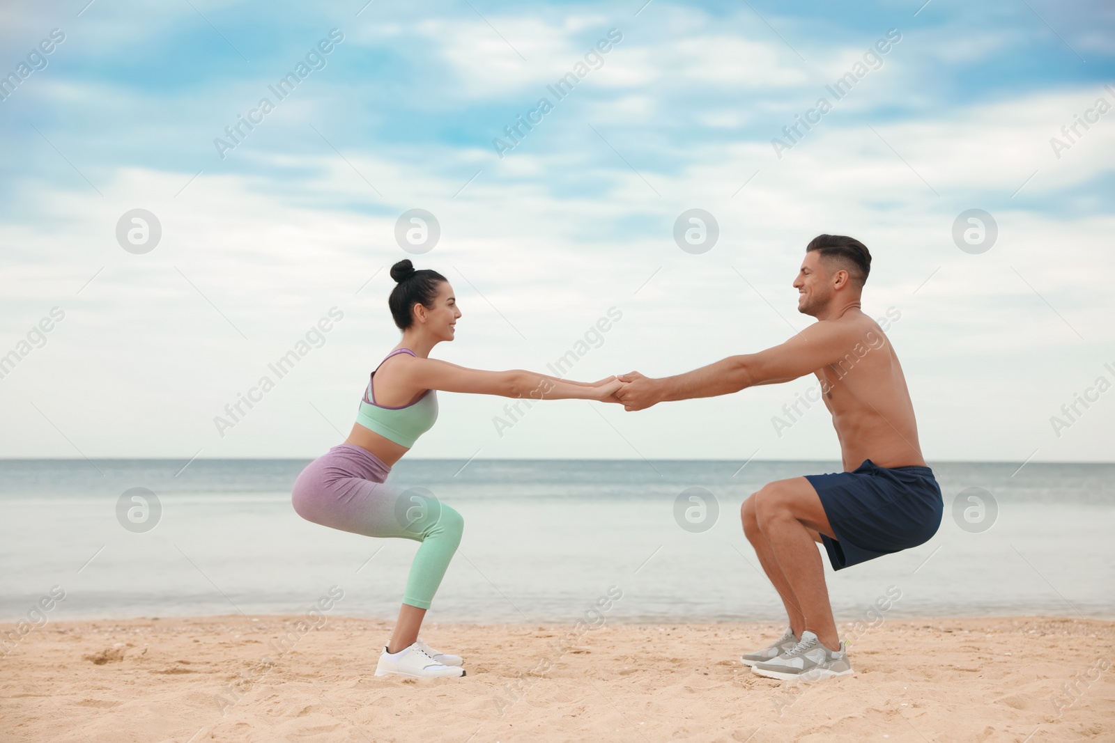 Photo of Couple doing exercise together on beach. Body training