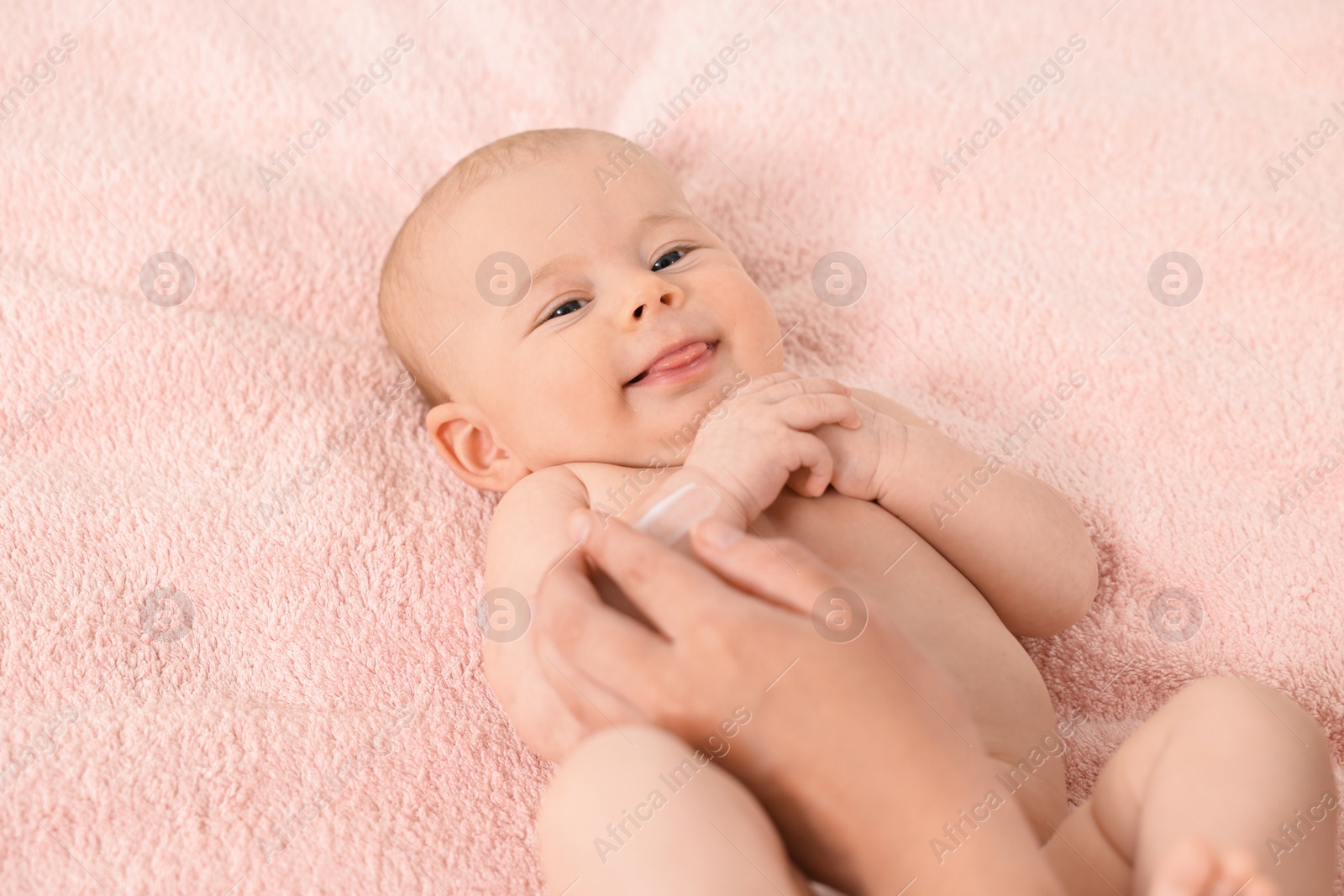 Photo of Woman applying body cream onto baby`s skin on bed, closeup