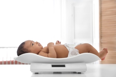 Photo of African-American baby lying on scales in light room