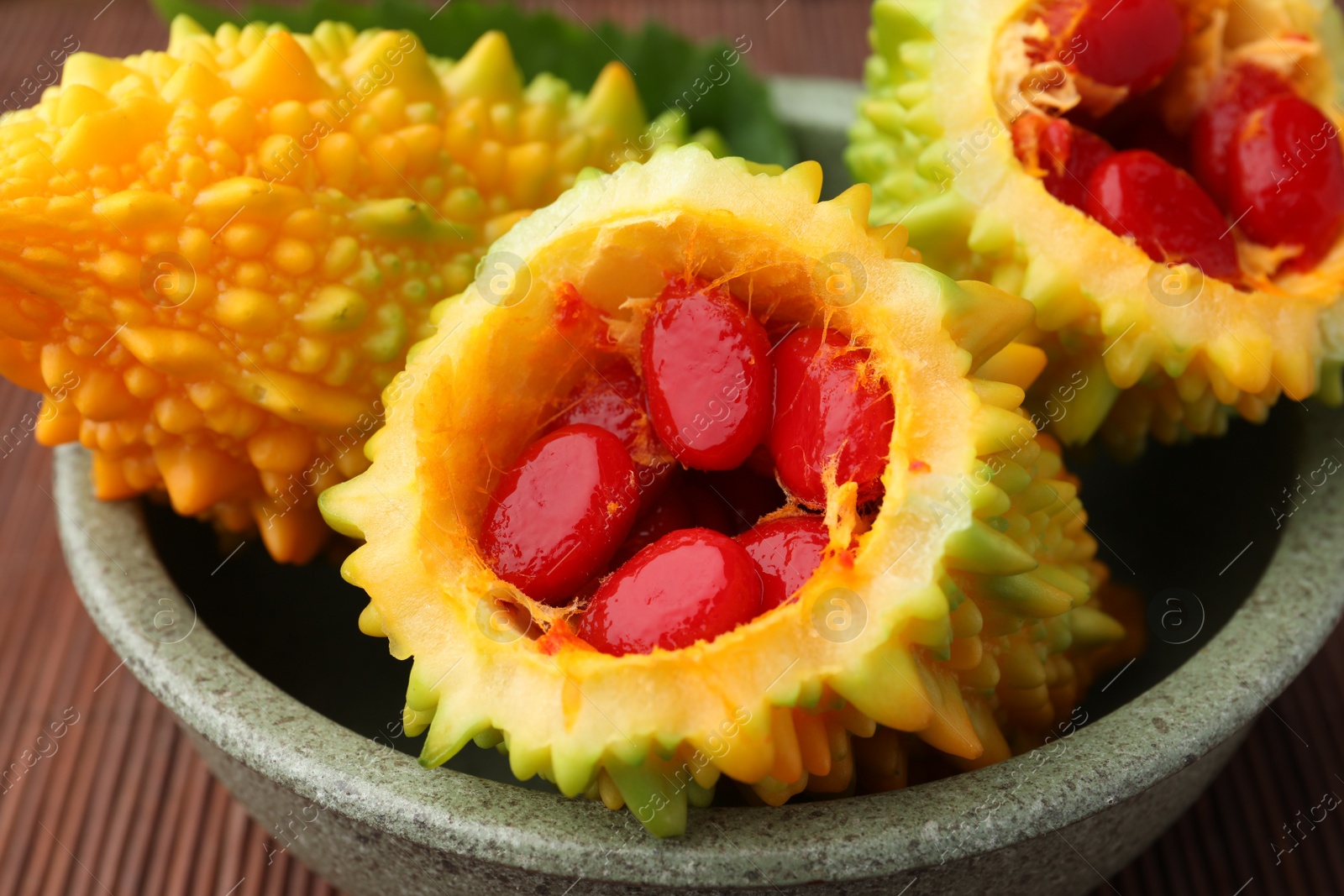 Photo of Many fresh bitter melons in bowl on table, closeup