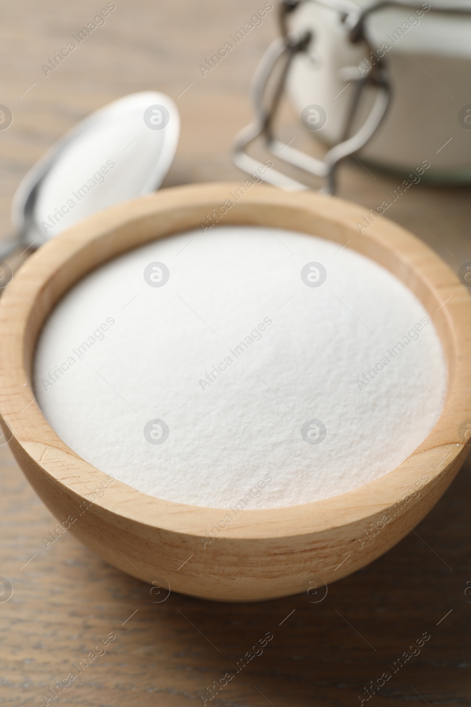 Photo of Baking soda in bowl on wooden table, closeup