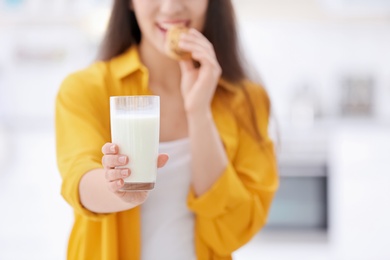 Photo of Beautiful young woman drinking milk with cookies at home