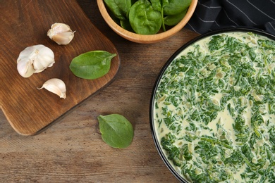 Photo of Tasty spinach dip on wooden table, flat lay