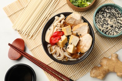 Delicious ramen served on white table, flat lay. Noodle soup