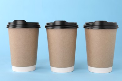 Photo of Paper cups with black lids on light blue background. Coffee to go