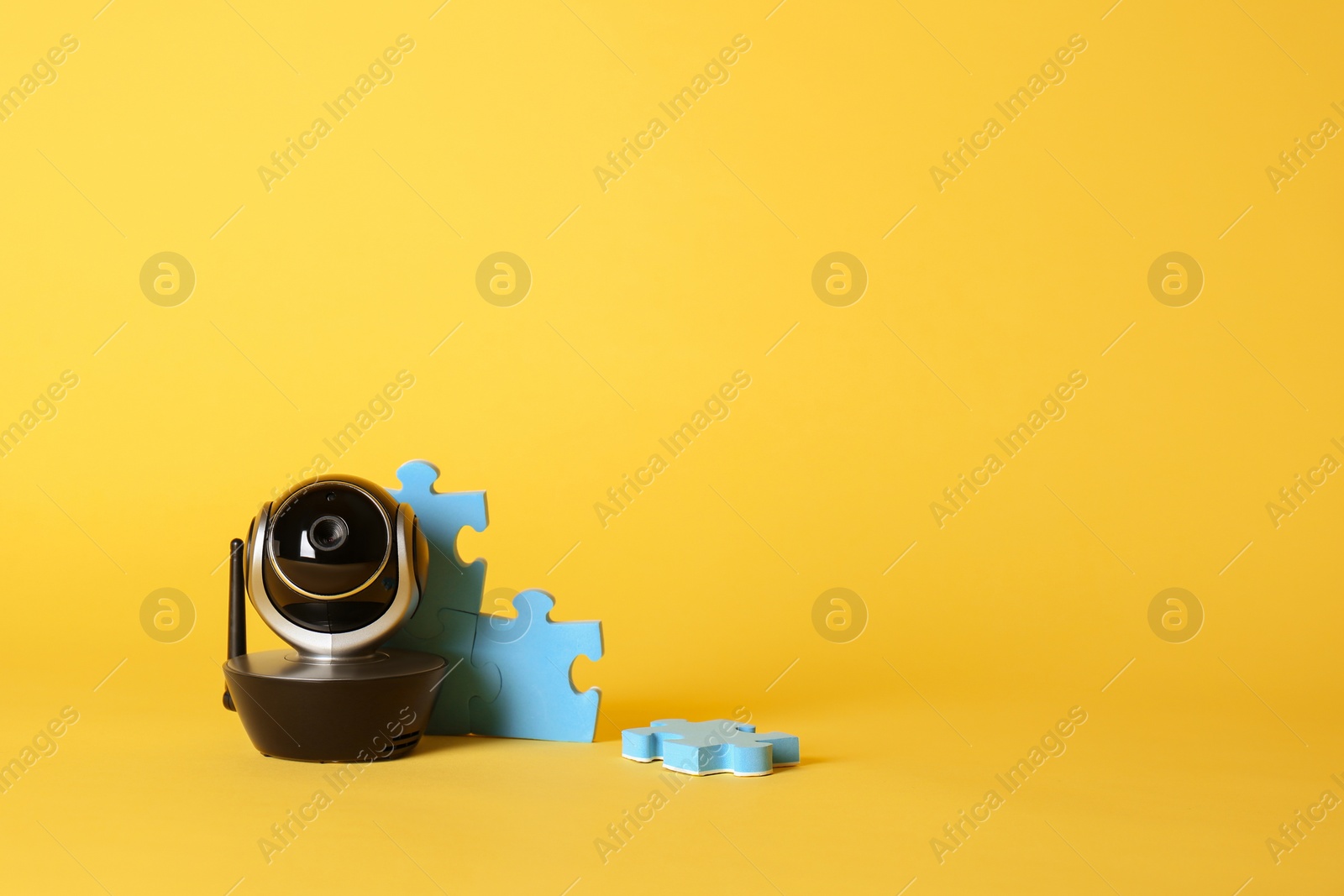 Photo of Modern CCTV security camera and child puzzle on color background. Space for text