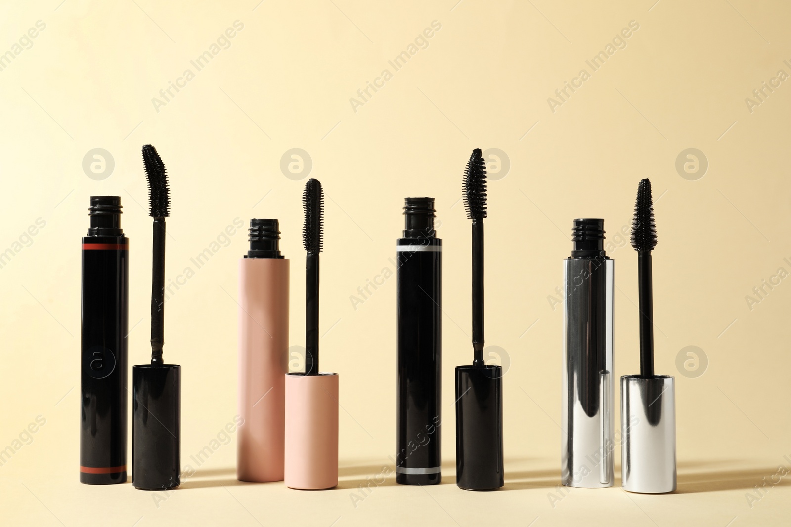 Photo of Different mascaras for eyelashes on beige background