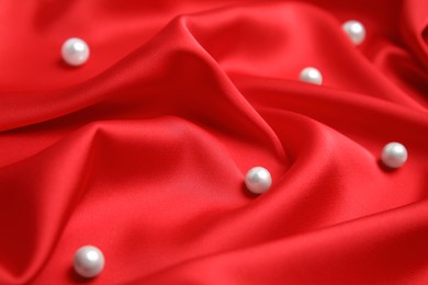 Many beautiful pearls on delicate red silk, closeup