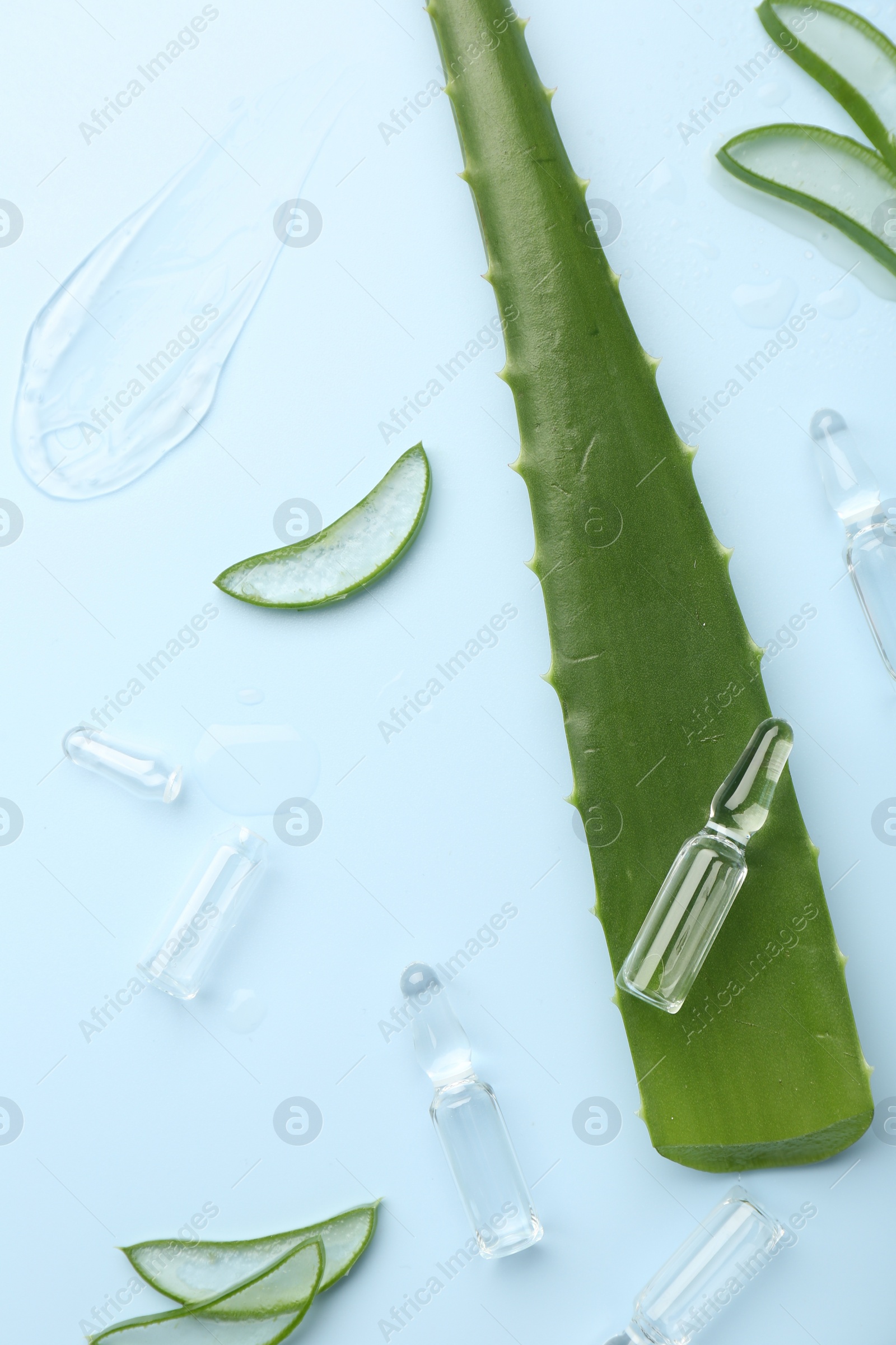 Photo of Flat lay composition with skincare ampoules and aloe leaves on light blue background