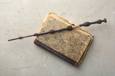 Magic wand and old book on light textured background, top view