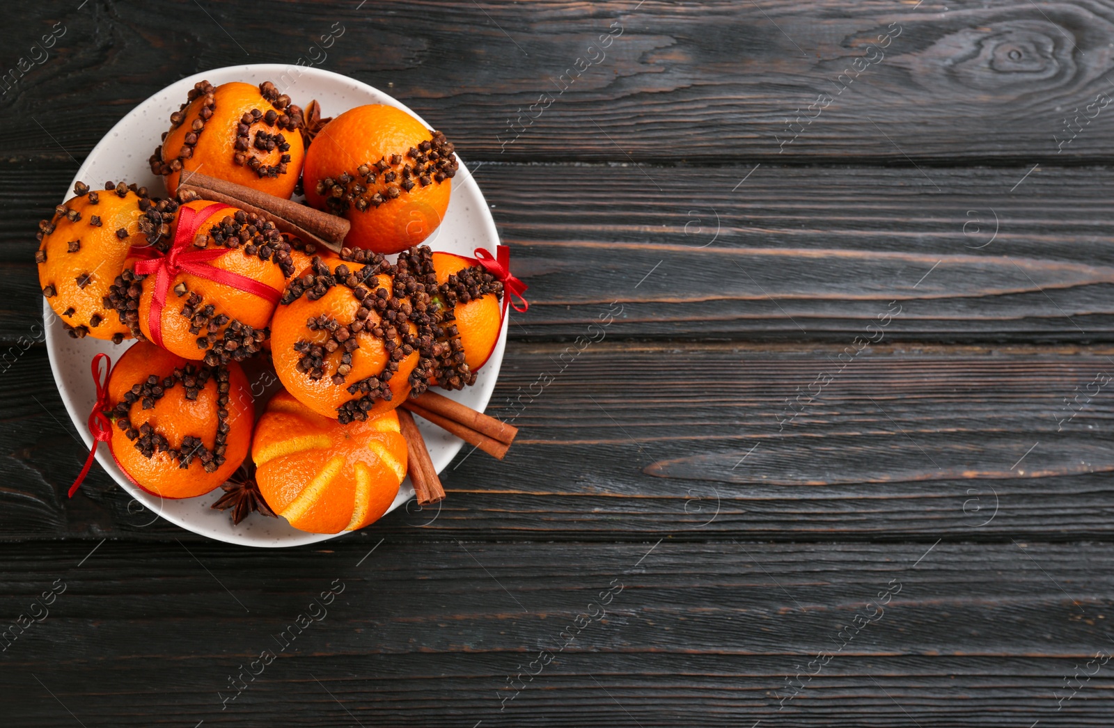 Photo of Pomander balls made of fresh tangerines and cloves on wooden table, top view. Space for text