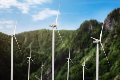 Image of Alternative energy source. Wind turbines and mountains outdoors 