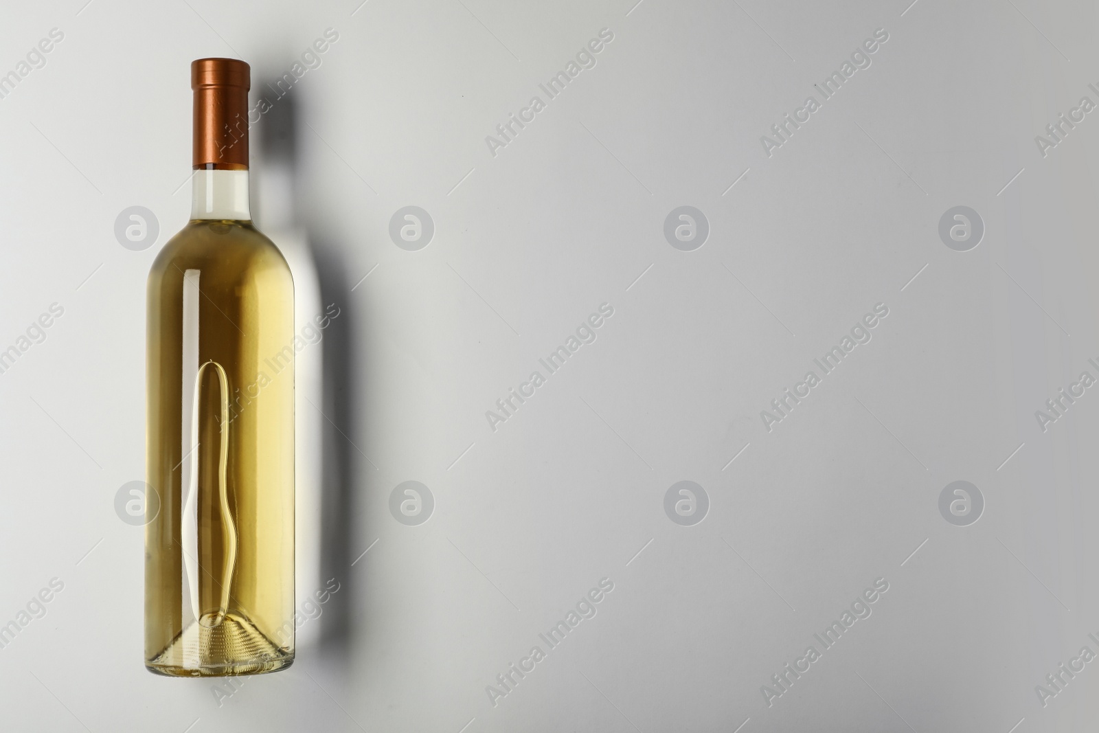 Photo of Bottle of expensive white wine on light background, top view