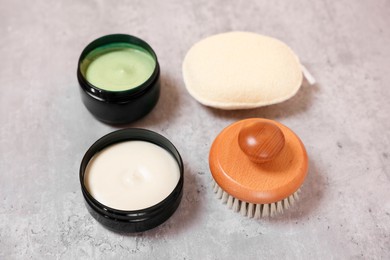 Natural body scrub, cream, brush and sponge on grey table