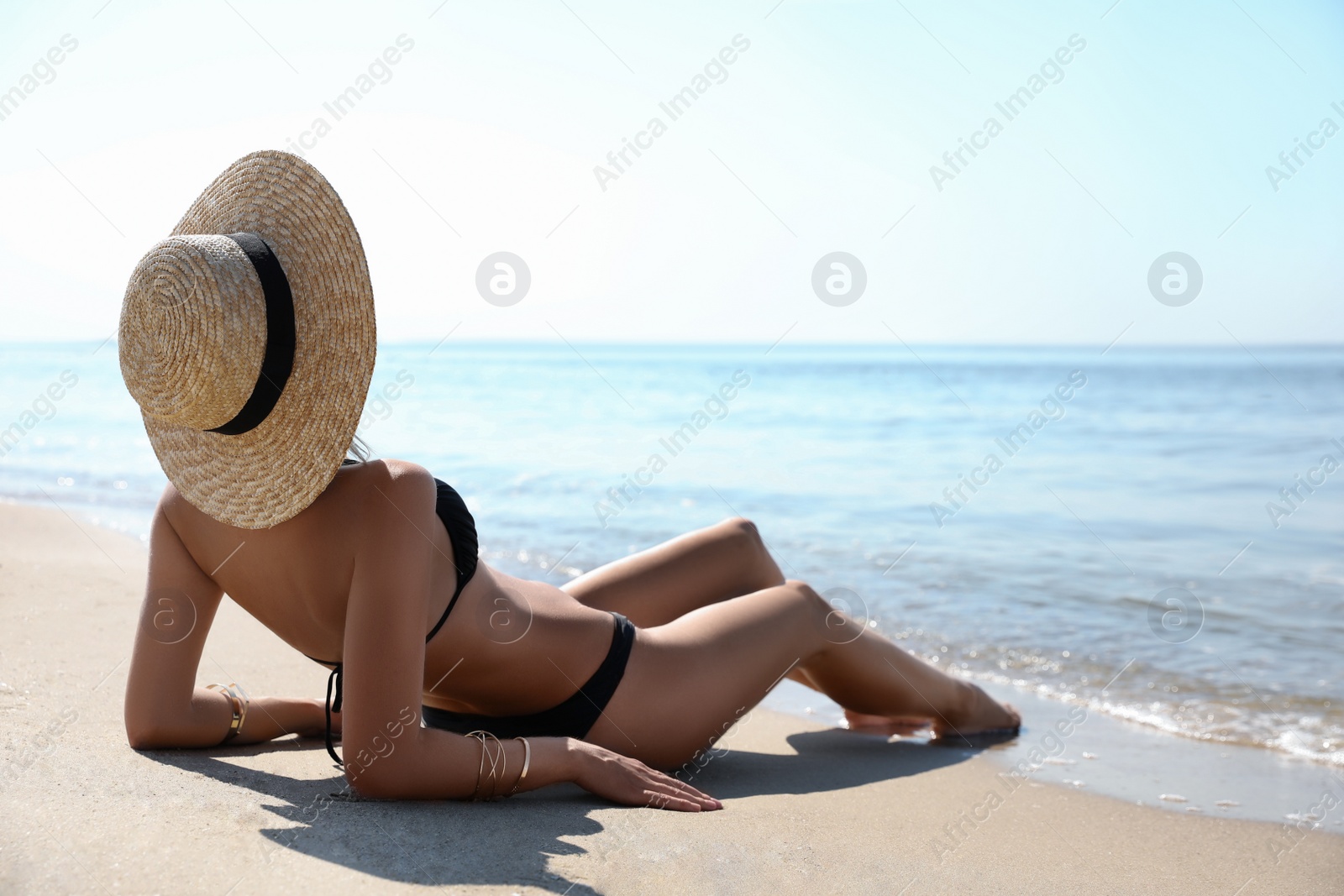 Photo of Young woman with beautiful body on sandy beach. Space for text