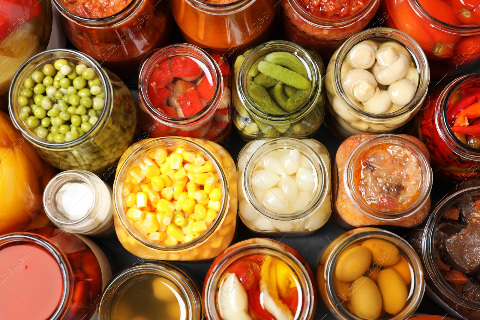 Photo of Open jars with pickled vegetables on grey table, flat lay