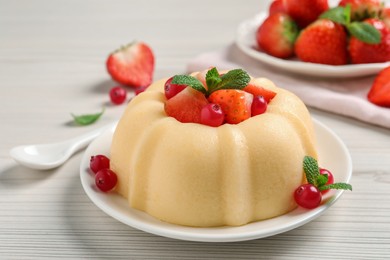 Photo of Delicious semolina pudding with berries on white wooden table