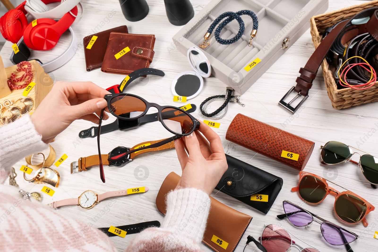 Photo of Woman holding glasses near table with different stuff, closeup. Garage sale