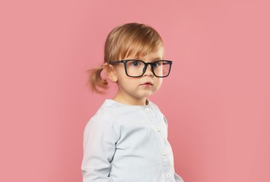 Photo of Cute little girl in glasses on pink background