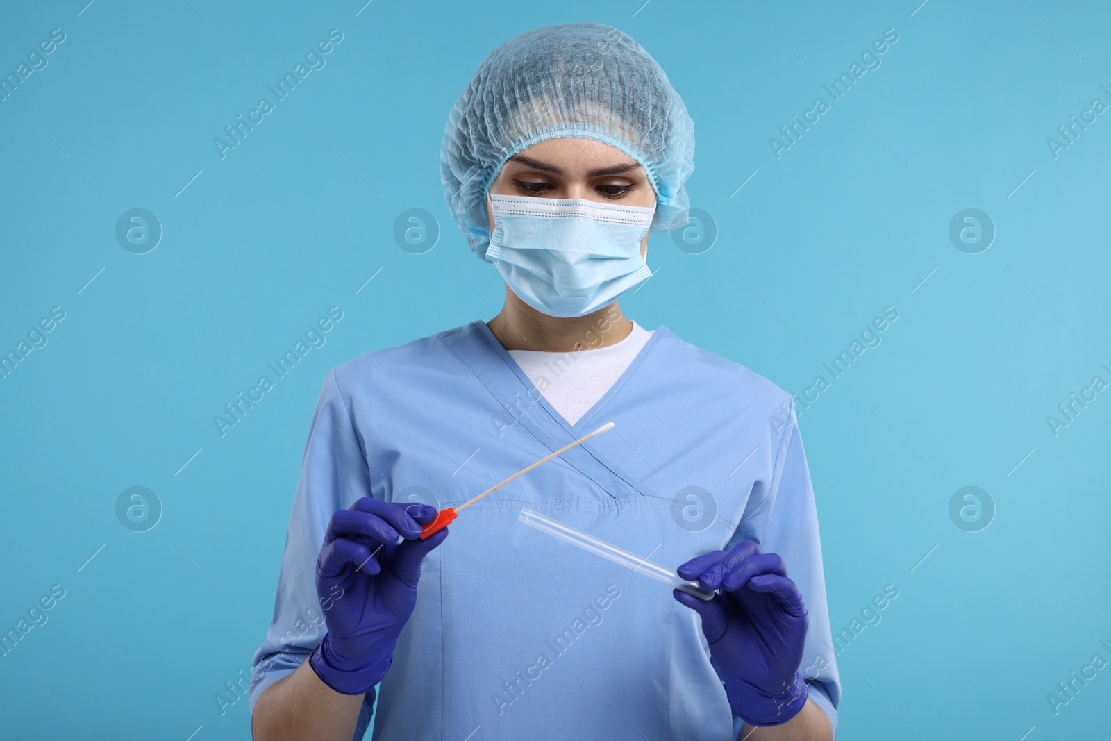 Photo of Laboratory testing. Doctor with cotton swab and tube on light blue background