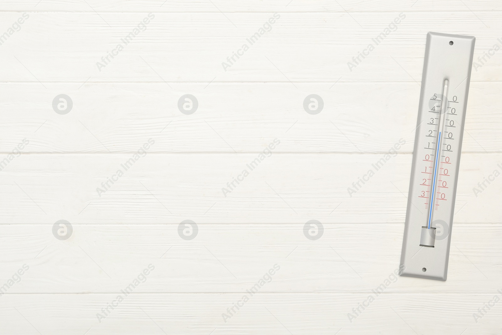Photo of Weather thermometer on white wooden background, top view. Space for text