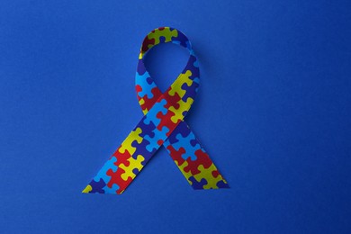 Image of World Autism Awareness Day. Colorful puzzle ribbon on blue background, top view