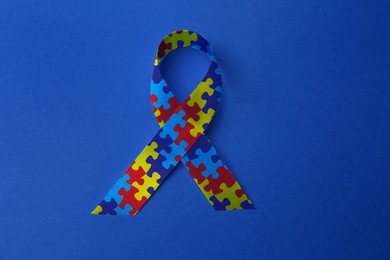 World Autism Awareness Day. Colorful puzzle ribbon on blue background, top view