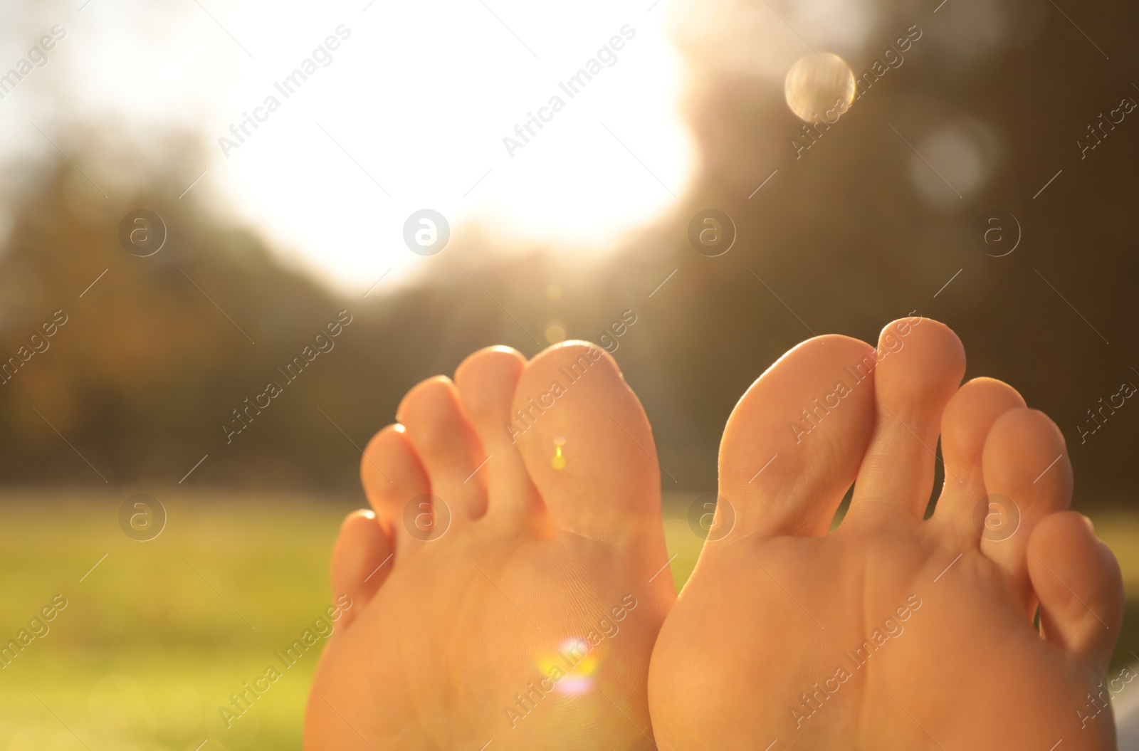 Photo of Young woman sitting barefoot outdoors, closeup view