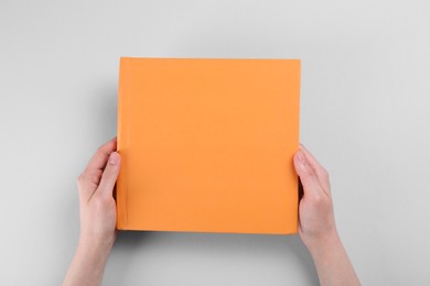 Woman with photo album at light table, top view