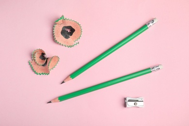 Photo of Pencils, sharpener and shavings on pink background, top view