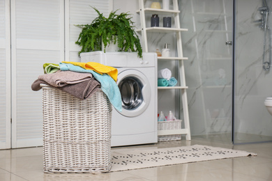 Photo of Wicker basket with laundry and washing machine in bathroom