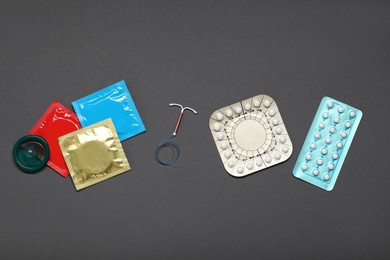 Photo of Contraceptive pills, condoms and intrauterine device on grey background, flat lay. Different birth control methods